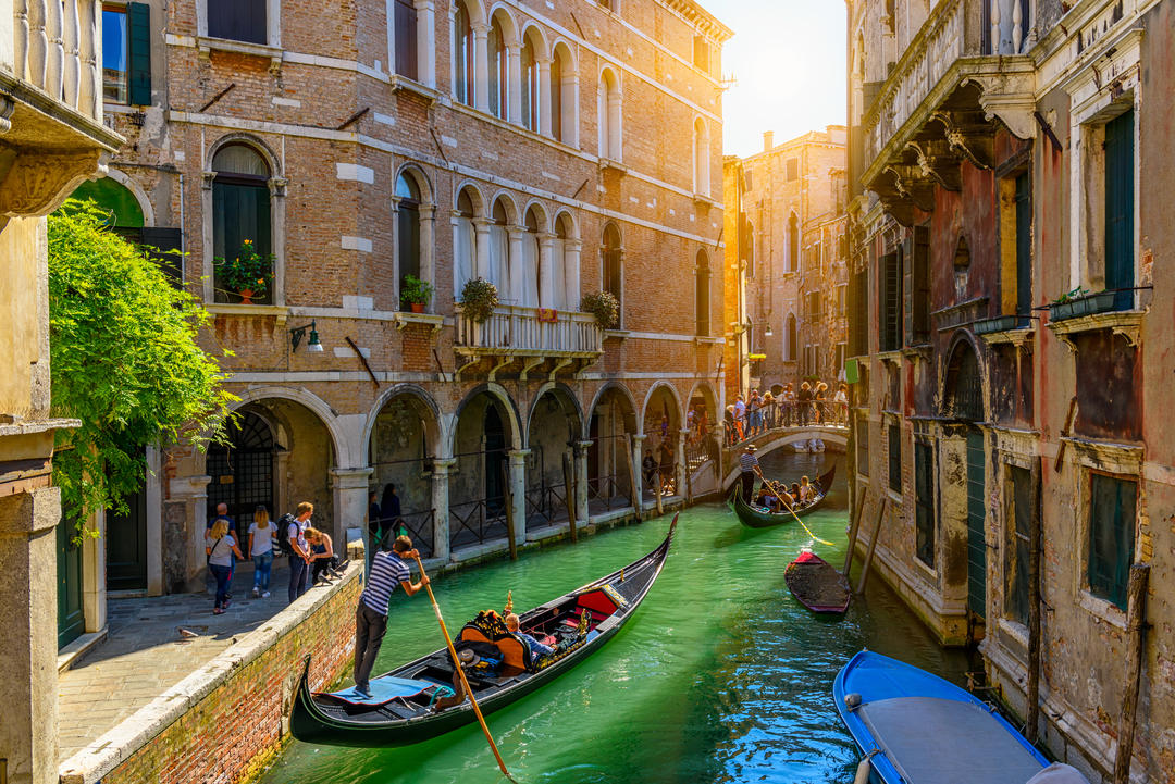 Вузький канал із гондолою та мостом у Венеції.