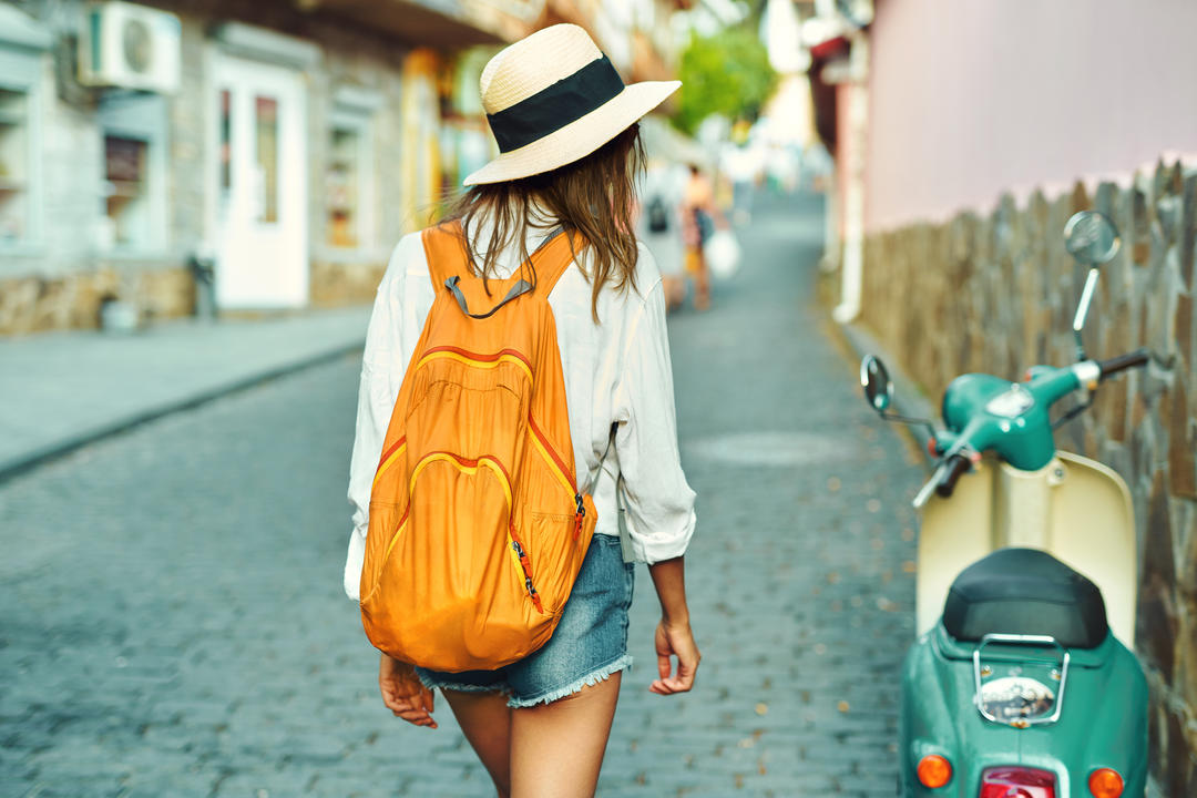 Дівчина в солом'яному капелюсі і помаранчевий рюкзак.