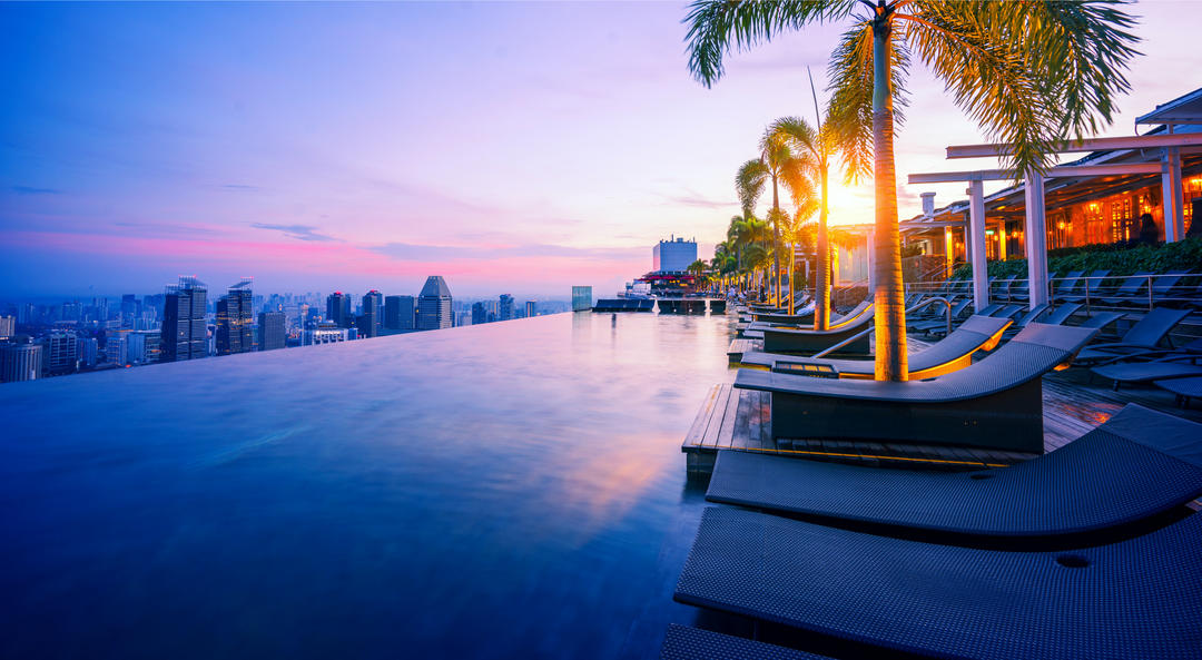 Панорамний басейн з лежаками та пальмами на даху готелю
