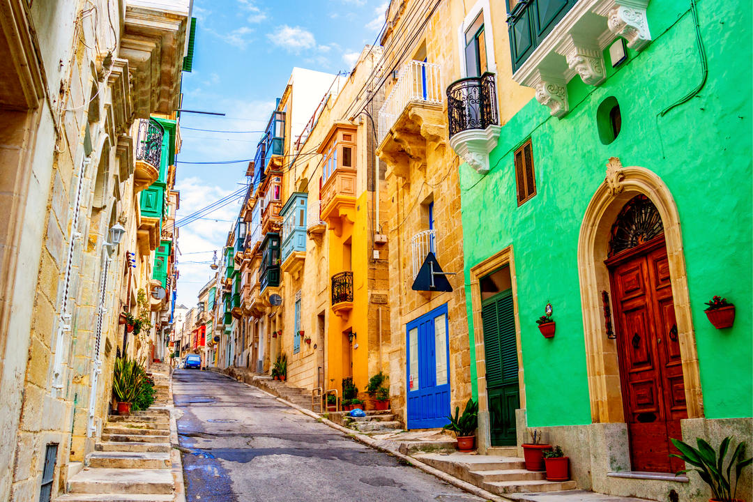 Вузька барвиста вулиця з типовою мальтійською архітектурою.