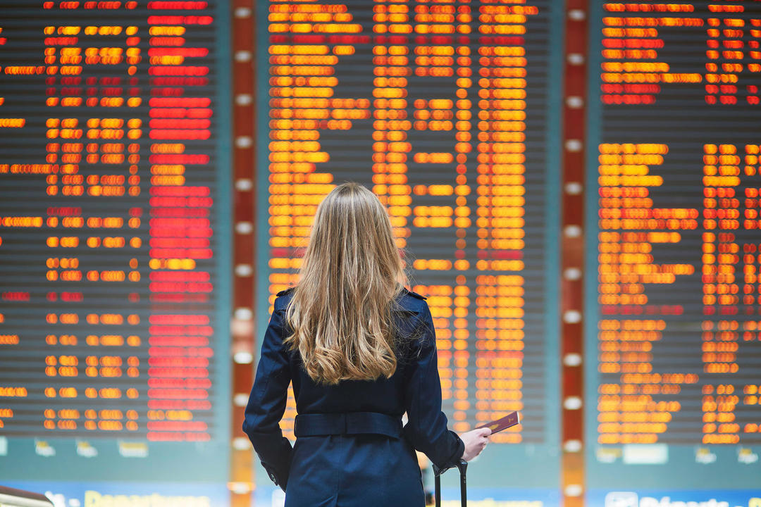 Дівчина в міжнародному аеропорту дивиться на дошку польоту