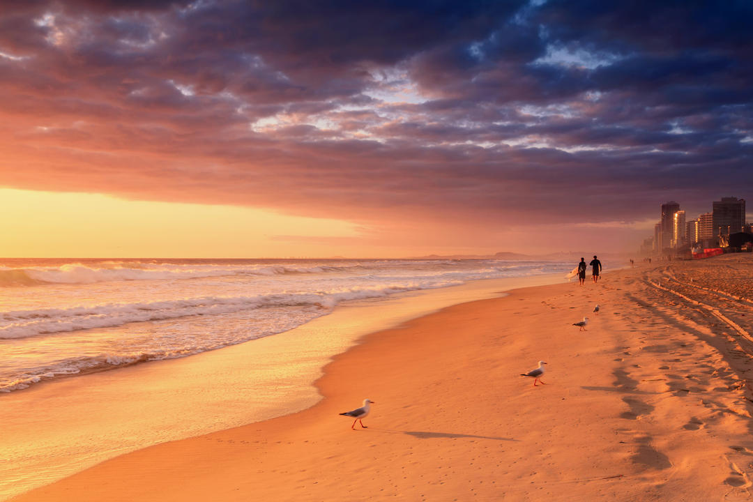 Серфери гуляють пляжем на світанку