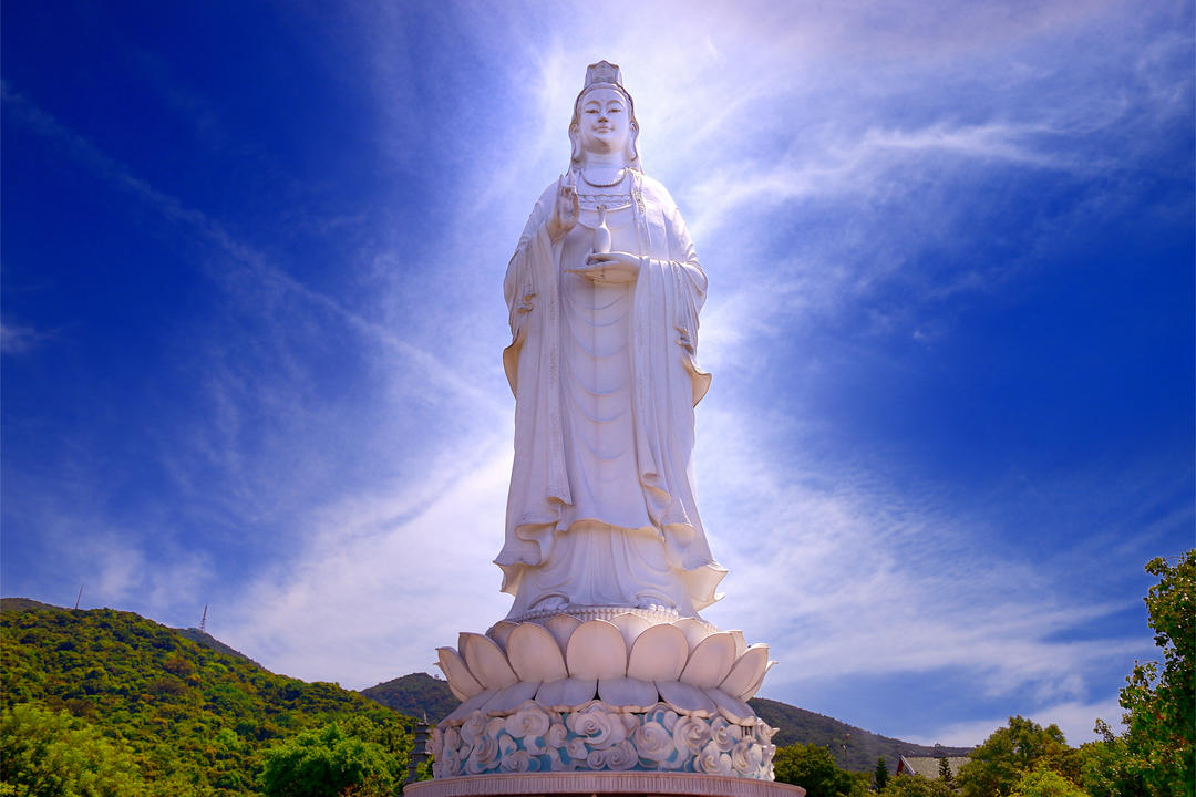 Біла стаття Будди на тлі синього неба.