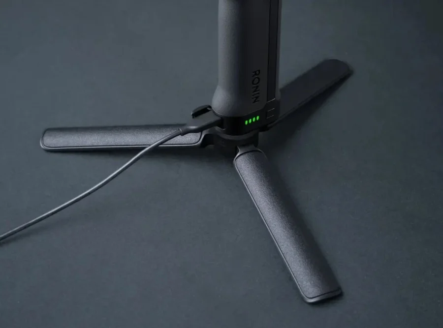 Рукоять-штатив стабілізатора DJI Ronin RS 5, підключена до зарядки, збоку видно порт і корпус акумулятора